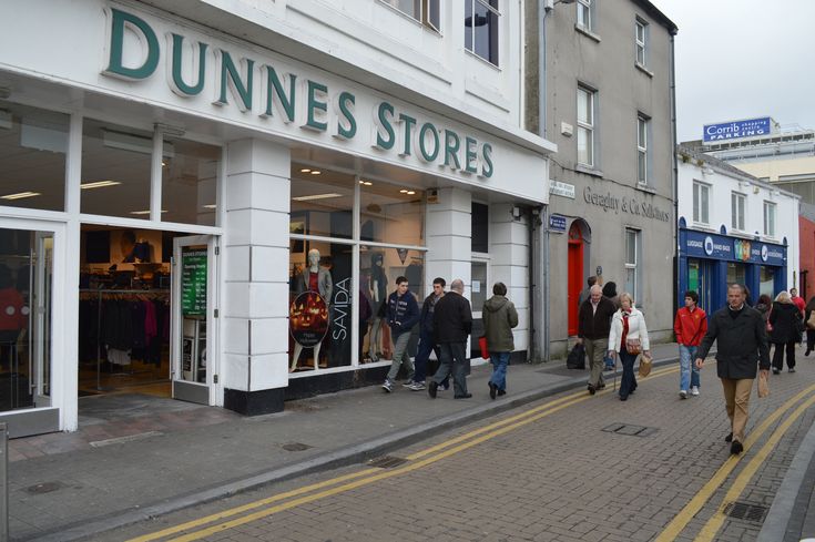 many people are walking down the street in front of dunnees stores on a cloudy day