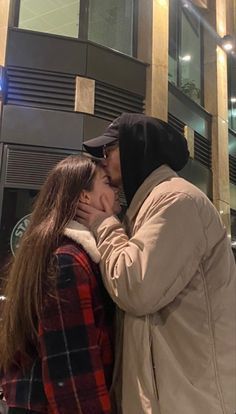 two people standing next to each other in front of a tall building with lights on