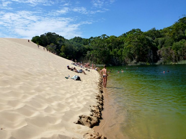 people are relaxing on the beach by the water's edge while others sunbathe