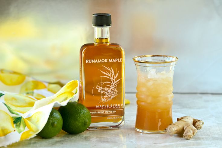 a bottle of rum next to a glass with lemon and ginger on the counter top