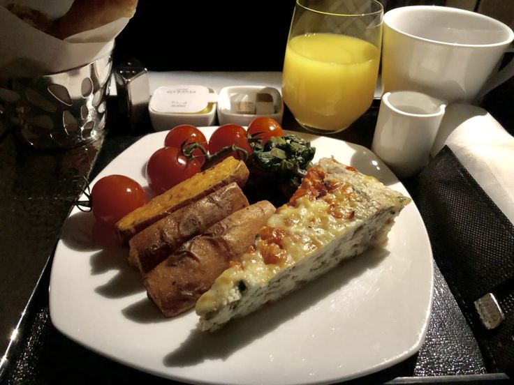 a white plate topped with food next to two glasses of orange juice and a glass of orange juice