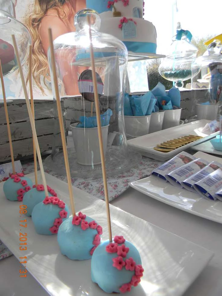 blue cake pops with pink sprinkles are on a white plate near other dessert items