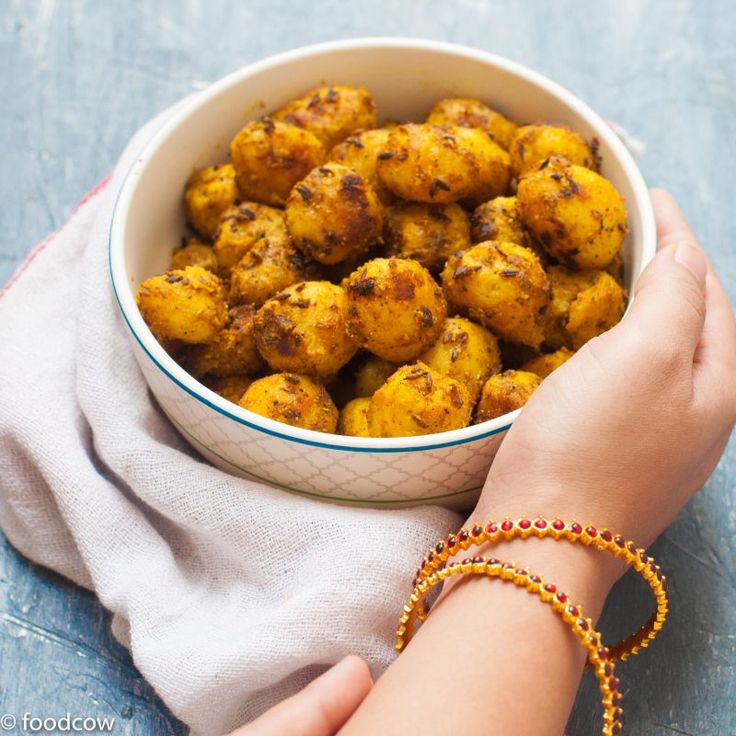 a person holding a bowl full of food on top of a blue tablecloth next to a napkin