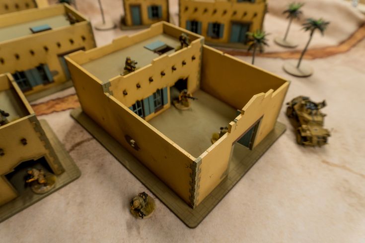 some toy soldiers are in front of a building with two small buildings on the ground