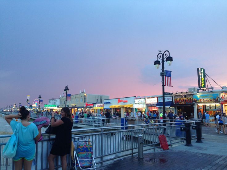 people are standing on the boardwalk at dusk