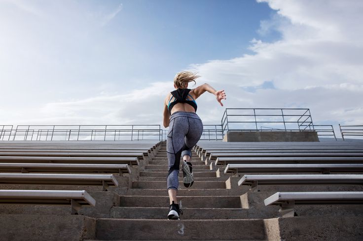 a woman is running up some steps in the air with her arms outstretched and head down