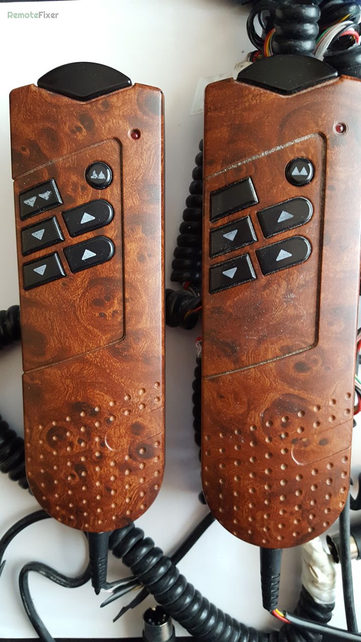 two wooden remote controls sitting next to each other on top of a white table with wires