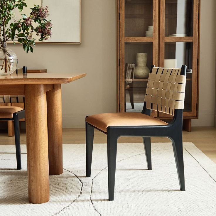 a dining room table with chairs and a vase filled with flowers on top of it