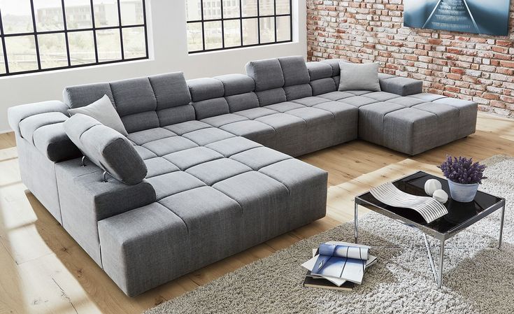 a large gray sectional sofa sitting on top of a wooden floor next to a window