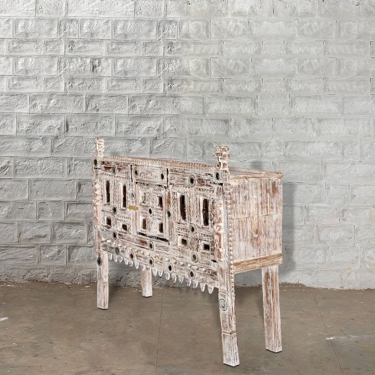 an old wooden cabinet sitting in front of a white brick wall on concrete flooring