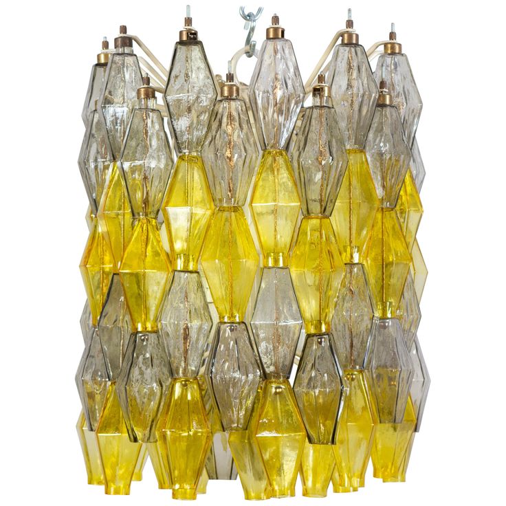 a yellow glass chandelier hanging on a white wall in the shape of hexagonals