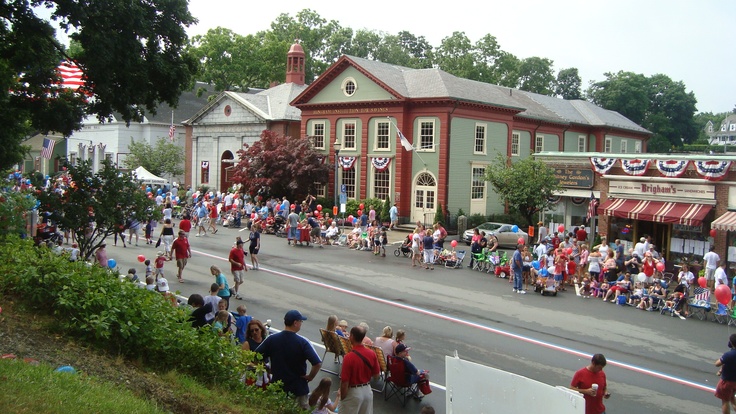 a group of people walking down a street in front of a red building with american flags on it