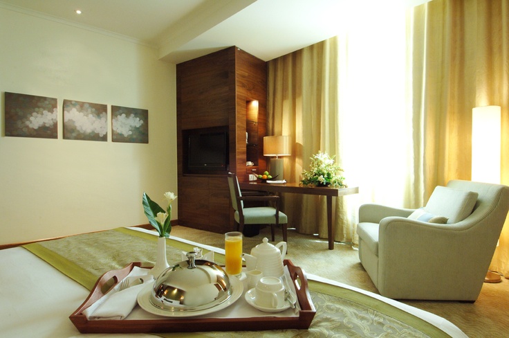 a tray with food on top of a bed in a room next to a chair