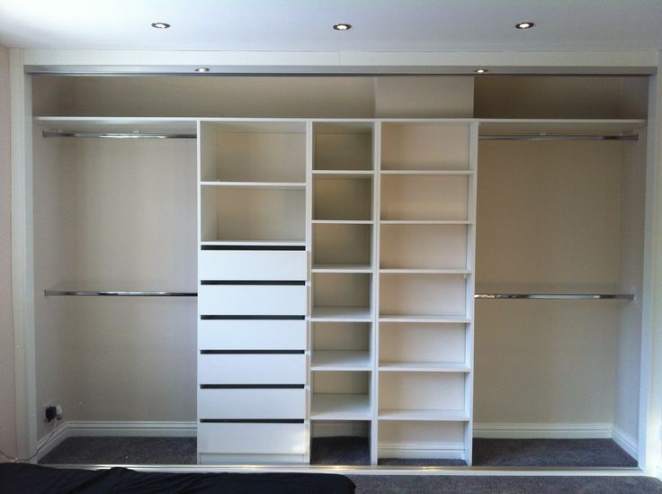 an empty walk in closet with white shelving and black carpeted flooring on the other side