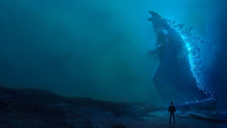 a man standing next to a giant godzilla in the ocean at night with its mouth open