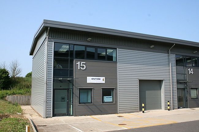 an empty parking lot next to a building with garages on each side and one car parked in front