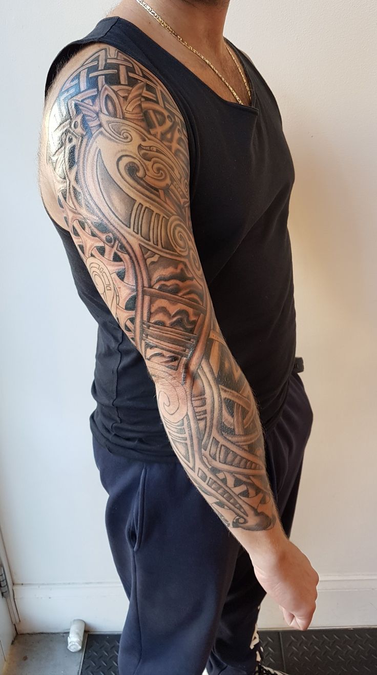 a man with a tattoo on his arm is standing in front of a white wall