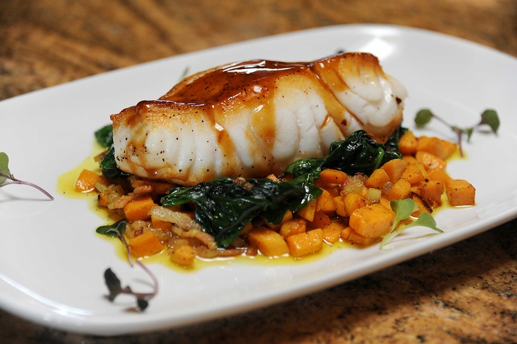 a white plate topped with fish and vegetables