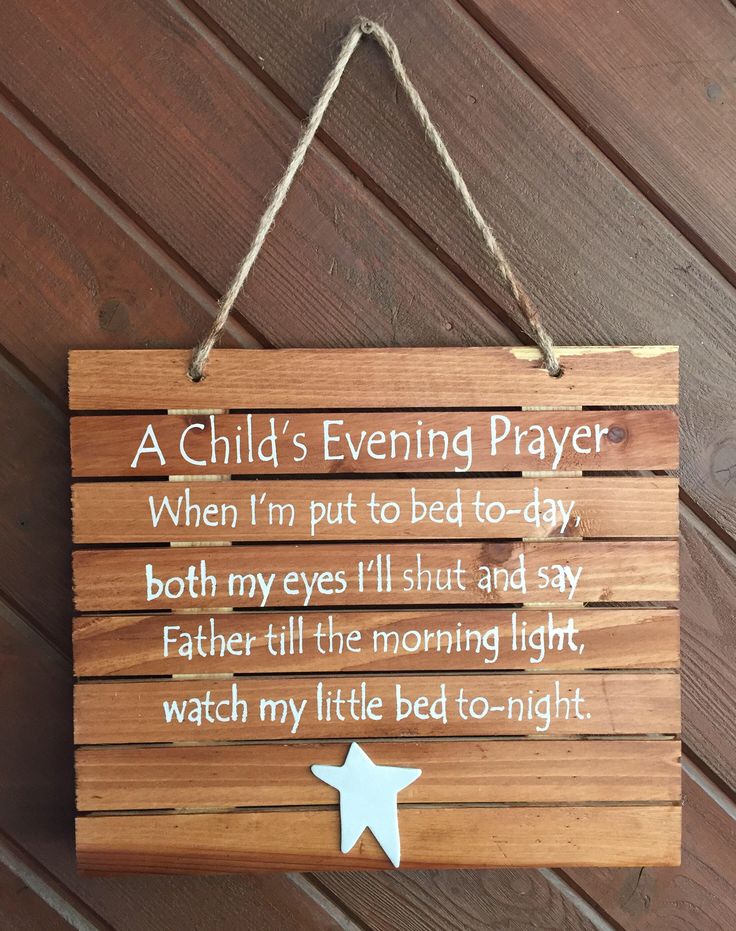 a child's evening prayer sign hanging on a wooden wall next to a door