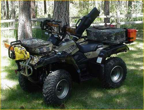 an atv parked in the grass next to a tree