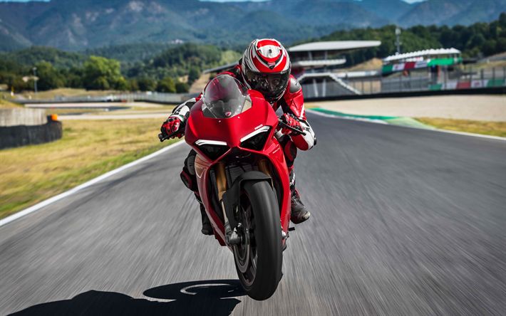 a man riding on the back of a red motorcycle down a curvy road