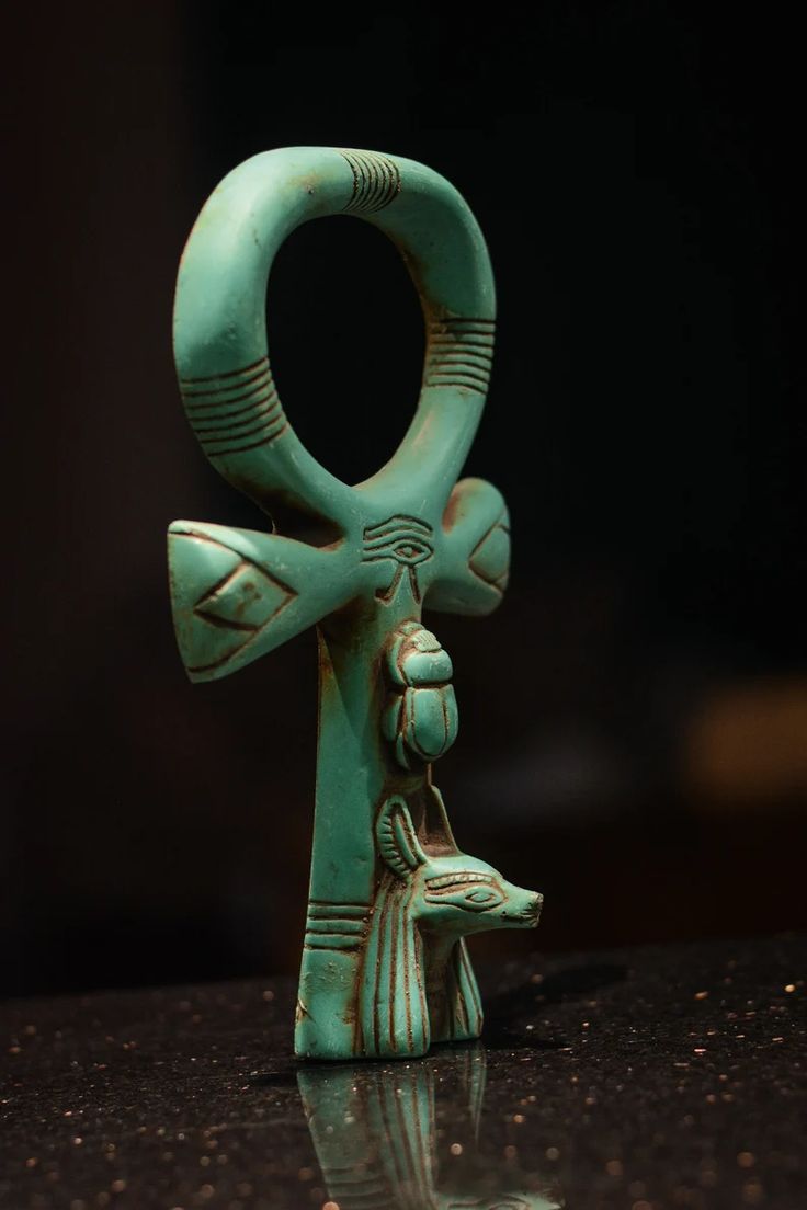 an egyptian figurine is displayed on a table with its reflection in the water