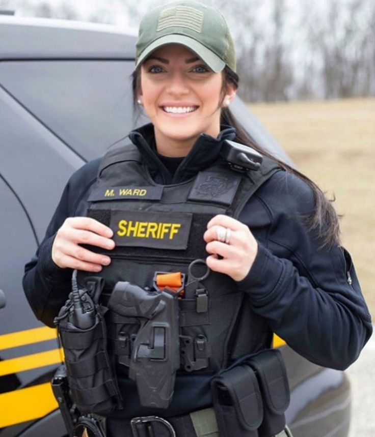 a woman wearing a sheriff uniform and holding something in front of her back pocket with the words sheriff on it