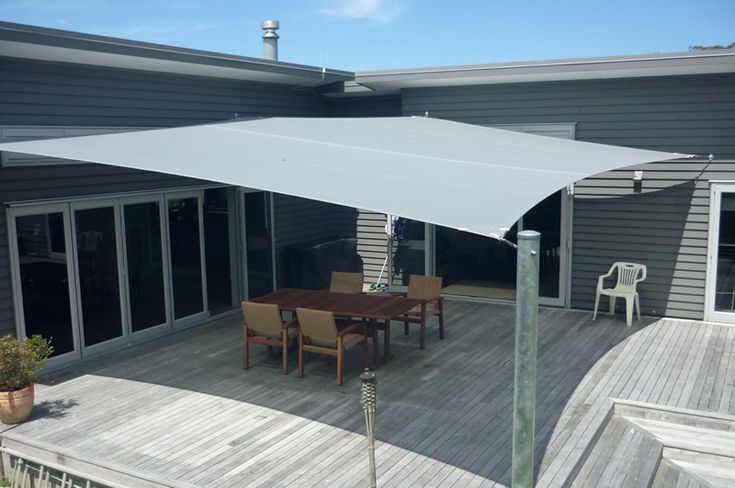 an outdoor deck with table and chairs under a large white awning over the dining area