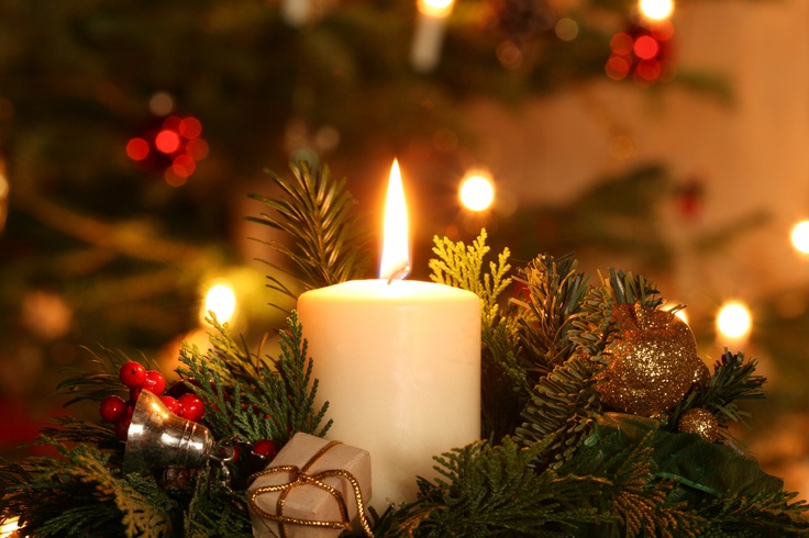 a lit candle sitting on top of a christmas wreath