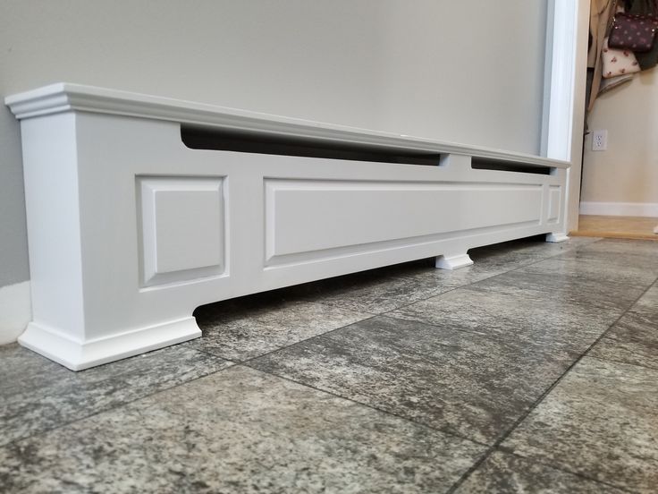 a white bench sitting on top of a tile floor next to a wall and door