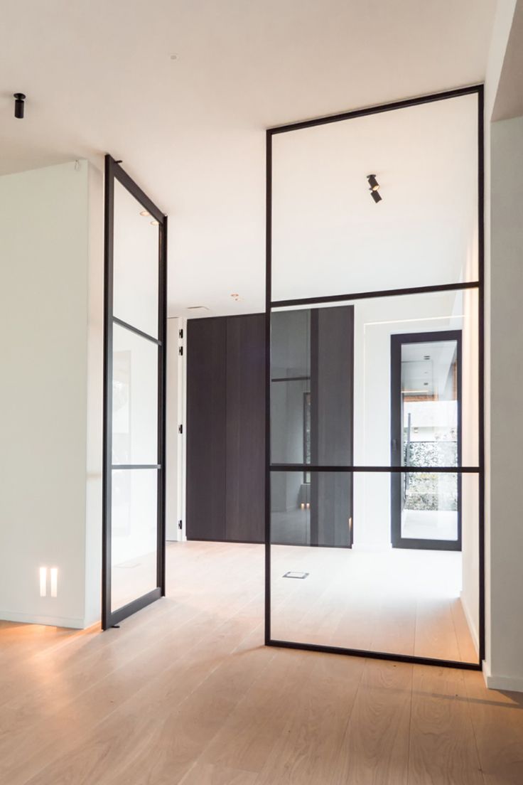 an empty room with wooden floors and black glass doors on the walls, in front of a white wall