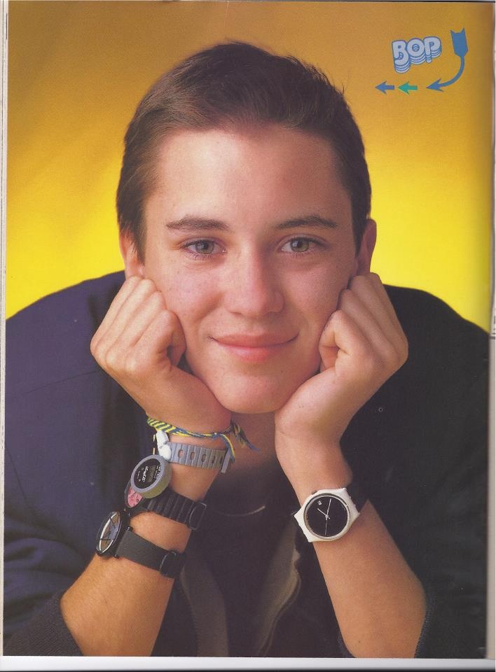 a young man with his hands on his face and wrist watches in front of him