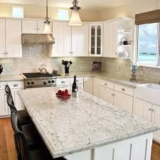 a kitchen with white cabinets and marble counter tops