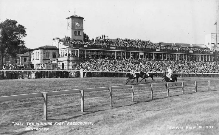 an old black and white photo of people riding horses in front of a race track