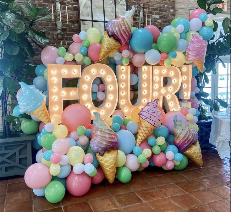 a sign that says four with ice cream cones and balloons around it in front of a brick wall