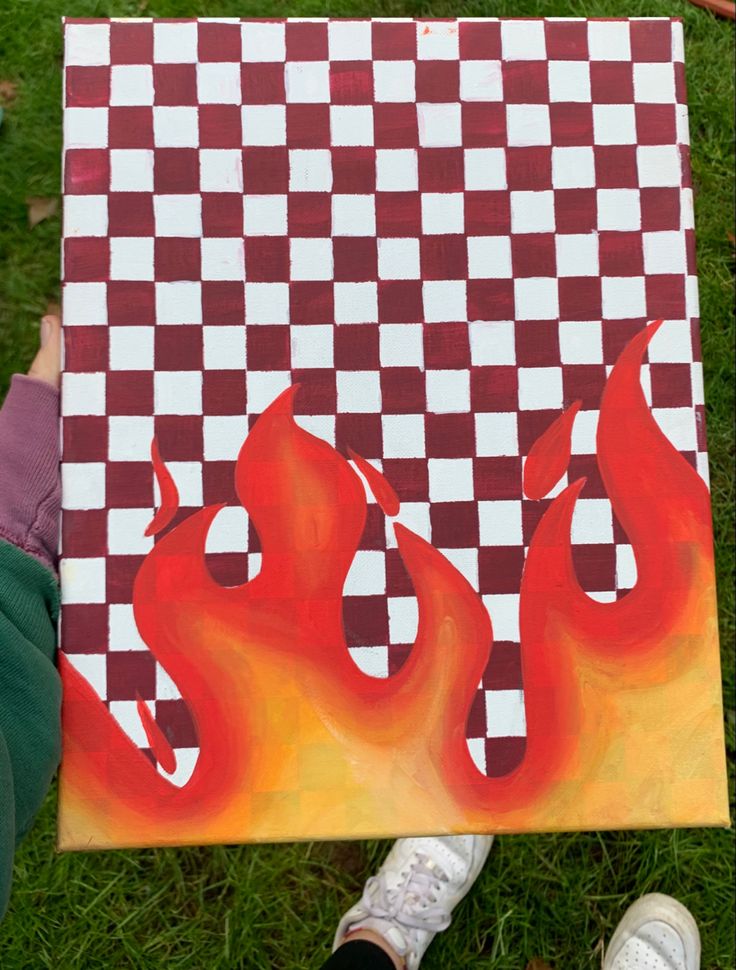 a person holding up a piece of art that looks like flames on a checkered board