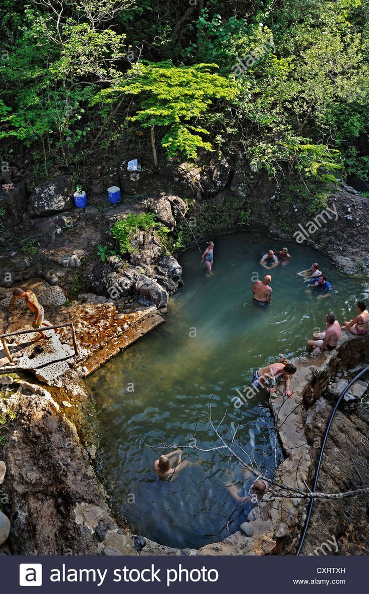 people are swimming in the river near some rocks and trees