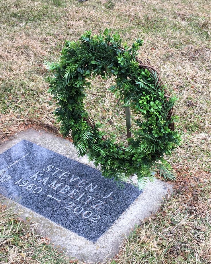 a wreath on top of a headstone in the grass