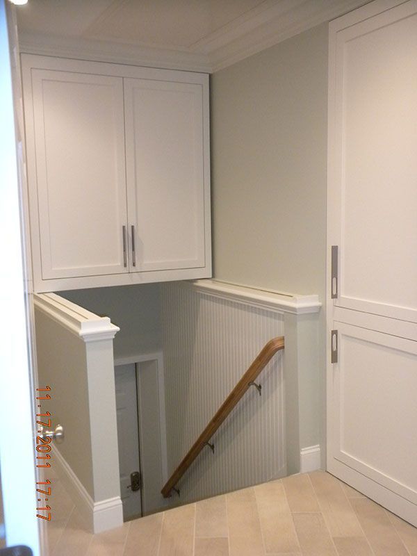 an empty room with white cupboards and stairs