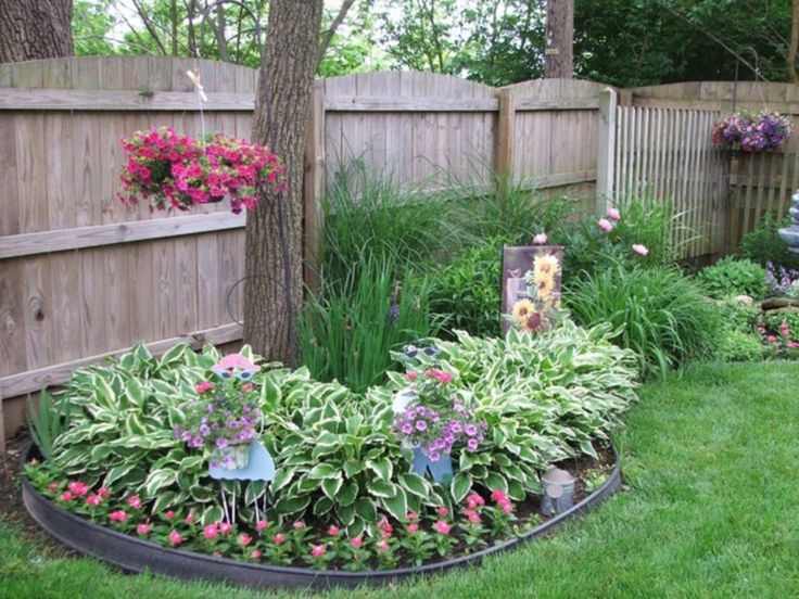 a garden filled with lots of flowers next to a wooden fence