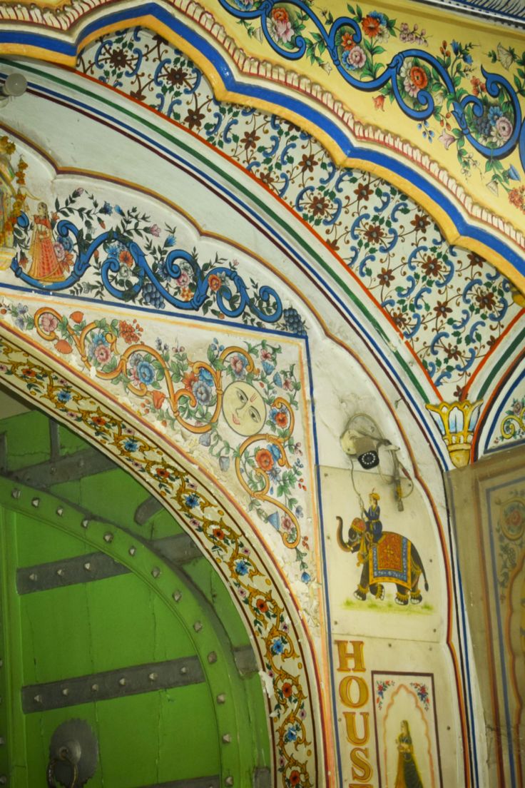 an ornately decorated entrance to a building with green doors and decorative designs on the walls