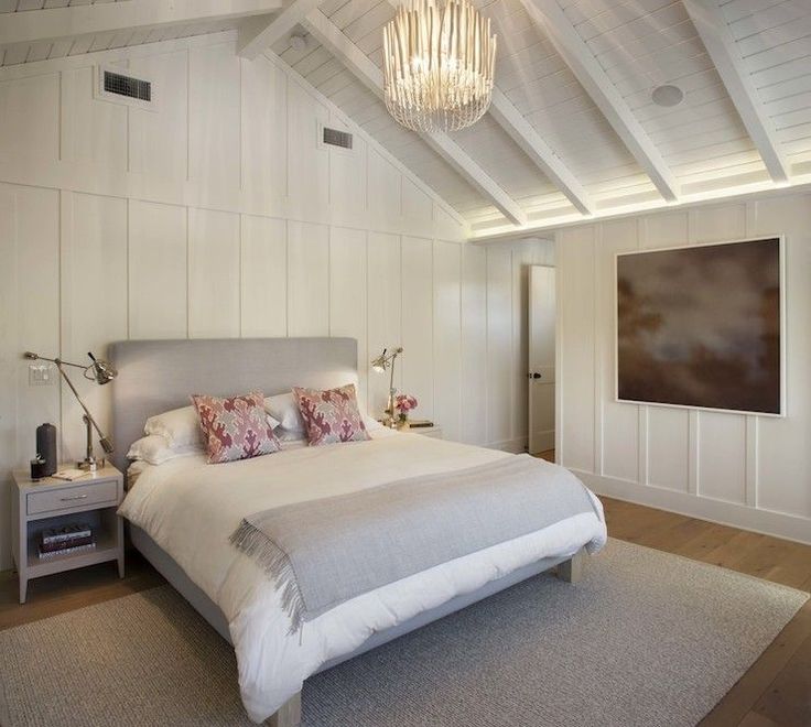 a bedroom with white walls and wood flooring has a chandelier hanging from the ceiling