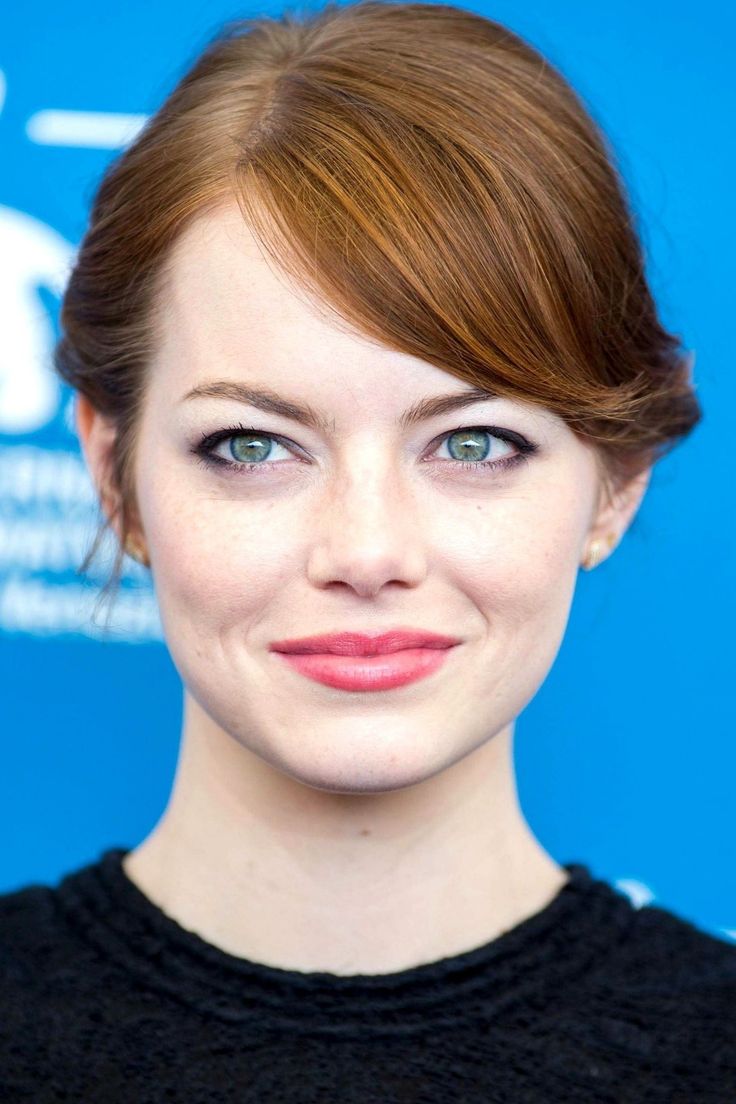 a close up of a person wearing a black shirt and smiling at the camera with blue eyes