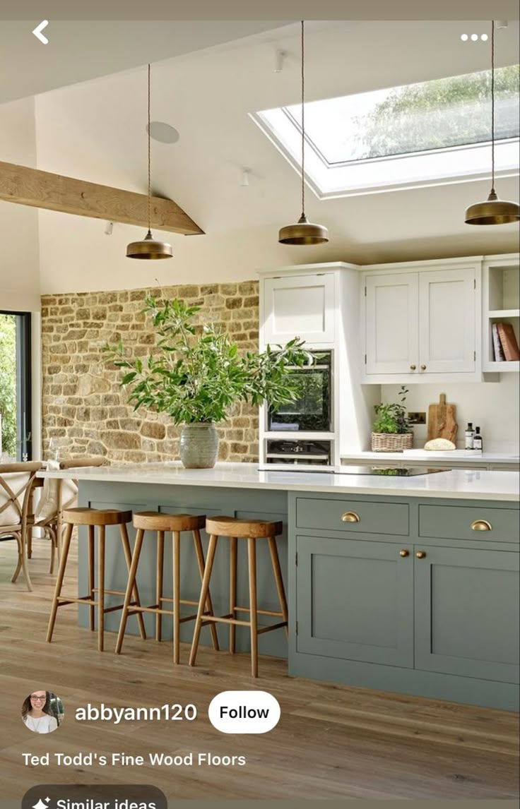 a large kitchen with an island and skylight above the countertop, surrounded by wooden flooring