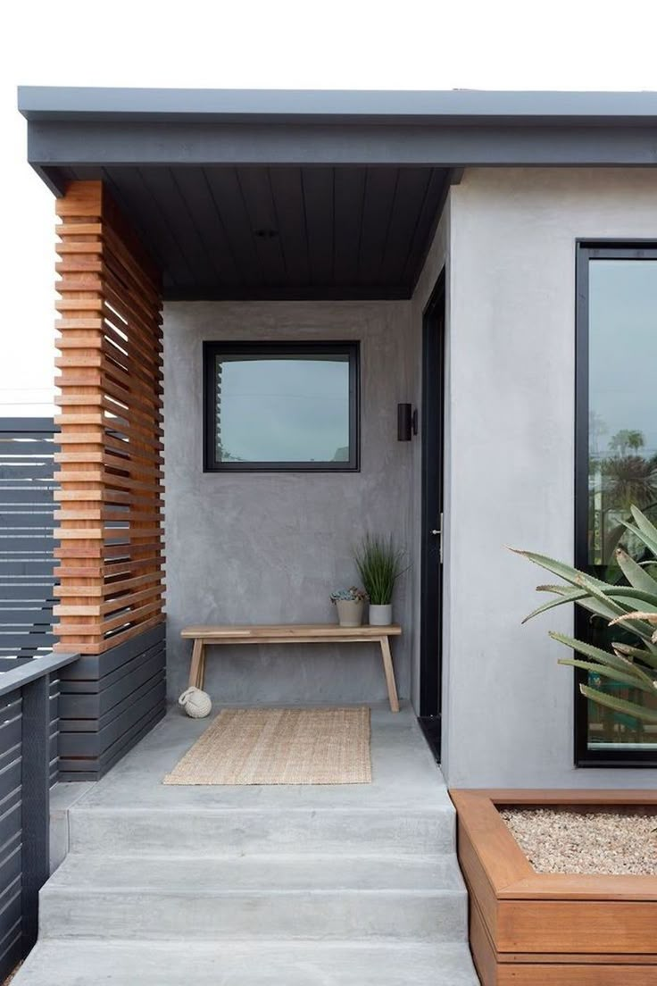 the front door is open and there are plants in pots on the steps leading up to the entrance