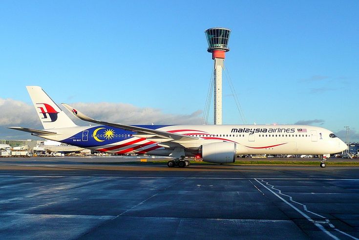 an airplane sitting on the tarmac in front of a control tower at an airport