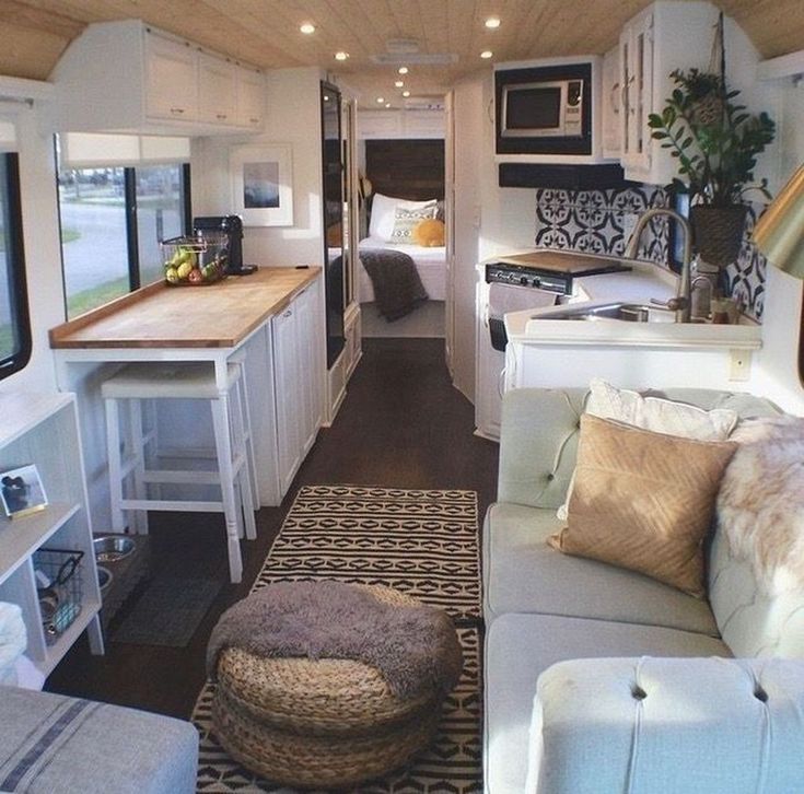 a living room with couches and a kitchen in the back ground, next to an rv