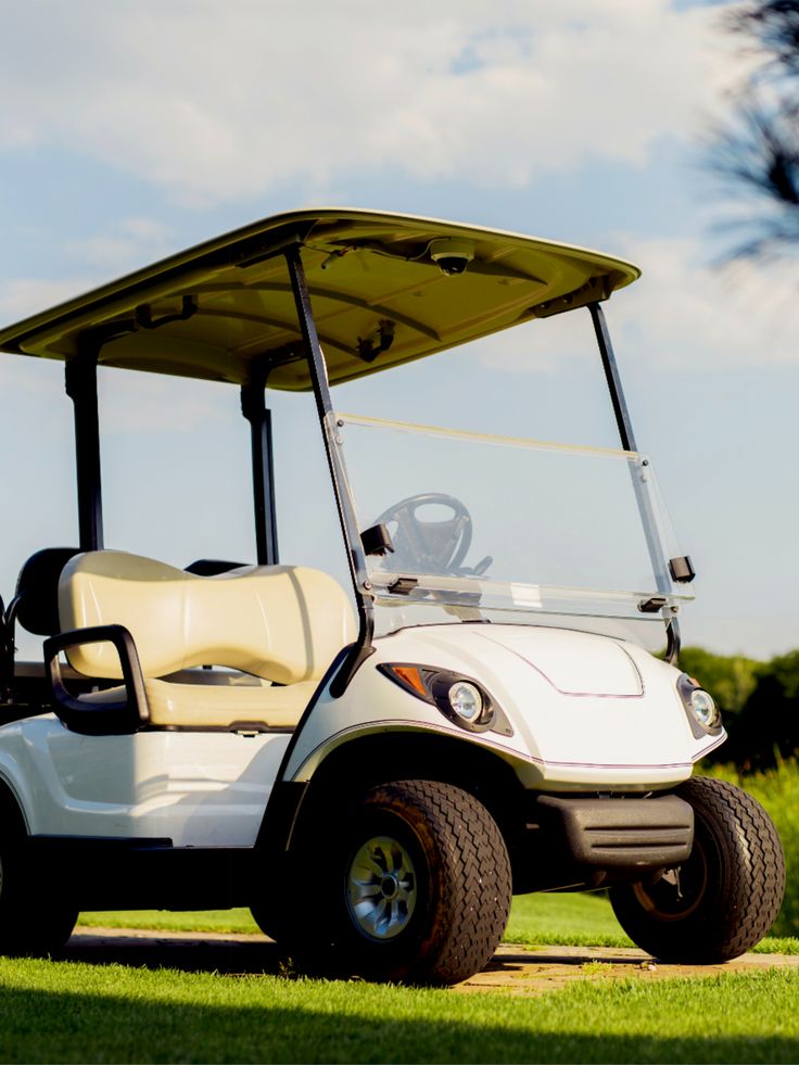 a white golf cart parked in the grass