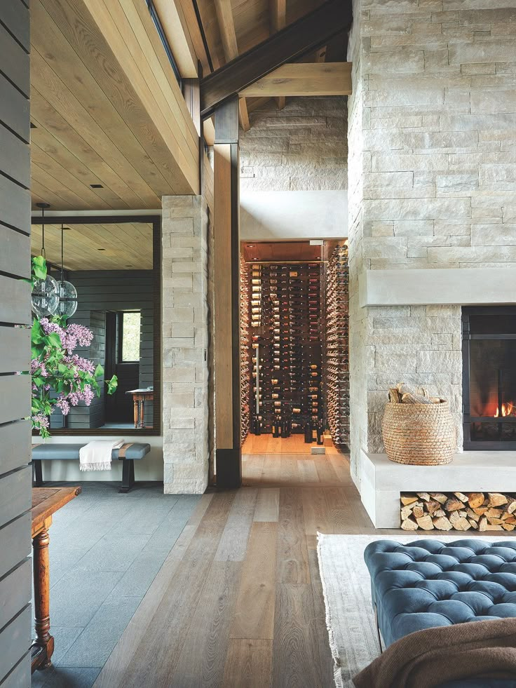 a living room filled with furniture and a fire place next to a wall covered in wine bottles