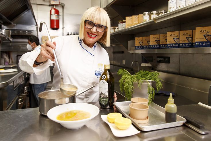 a woman in a chef's uniform is holding a ladle and mixing liquid